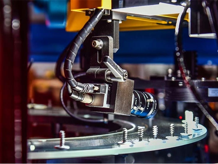 Industriel robotarm inspicerer metaldele med kamera