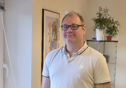 Mand smiler i et lyst kontor